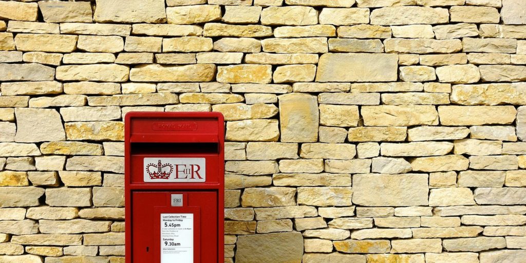 a red royal mail bost box in a brick wall