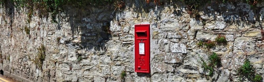 red royal mail post box in a stone wall