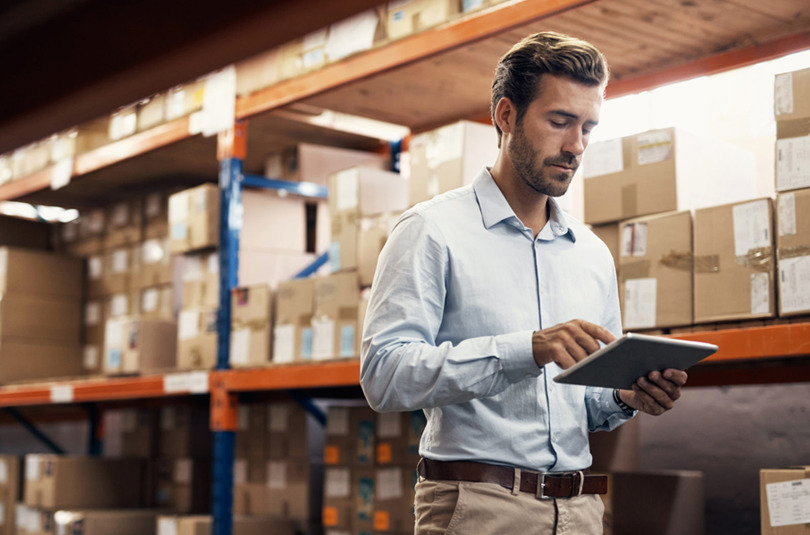 Photo of man in a warehouse checking Scurri's delivery management platform on a tablet device